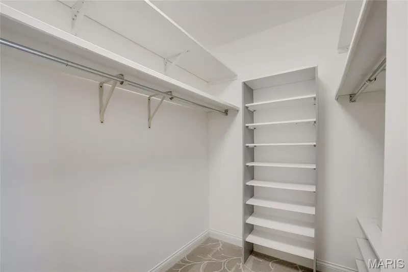 Walk-in closet featuring white built-in shelving, hanging rods, and a patterned carpet — 2508 Peppermill Lake Court, Chesterfield, MO 63005