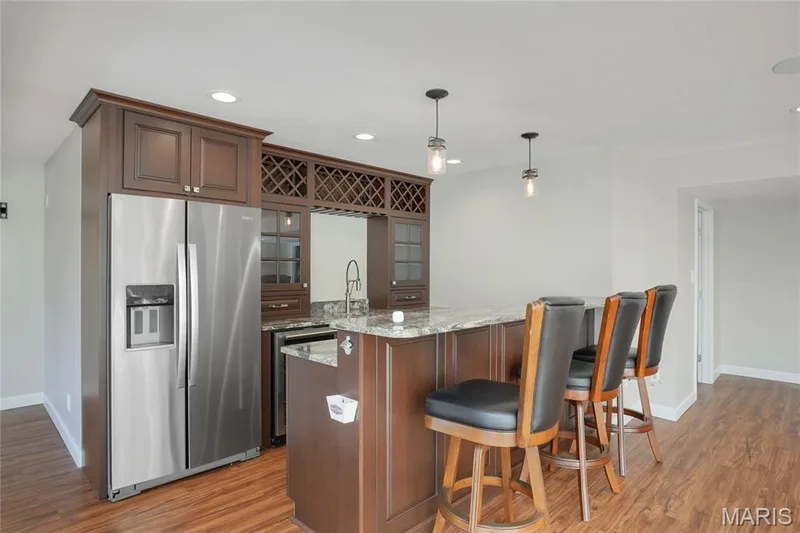 Recessed lighting, and a built-in bar with dark wood cabinetry, granite countertop, and stainless steel refrigerator — 2508 Peppermill Lake Court, Chesterfield, MO 63005