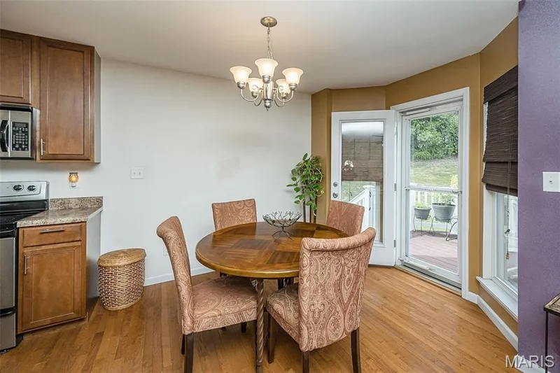 Wood-finish flooring, built-in cabinetry, stainless steel microwave, and French-style door leading to an outdoor deck — 500 Flowering Magnolia Drive, O'Fallon, MO 63366