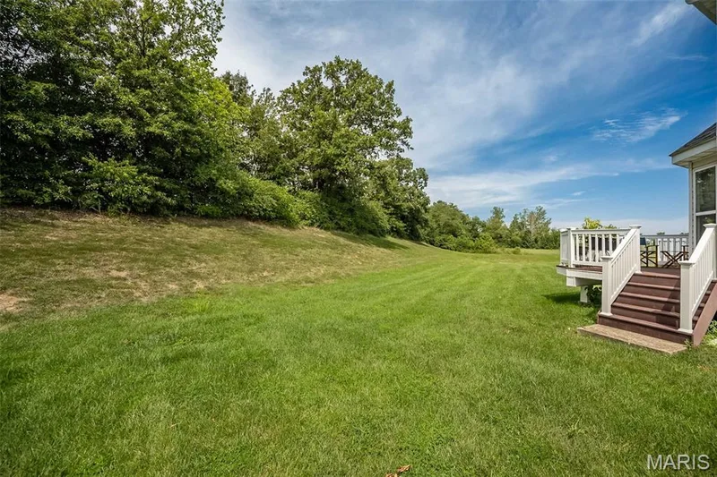 Expansive green lawn with mature trees and a multi-level deck — 500 Flowering Magnolia Drive, O'Fallon, MO 63366