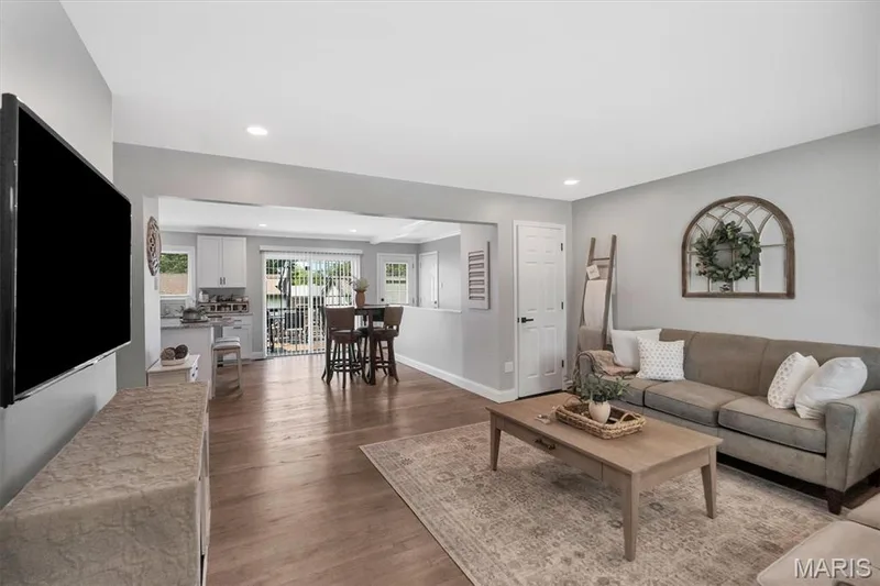 Open-concept living area with wood-finish flooring, recessed lighting, and a white interior door — 7 Saint Mark Drive, St Peters, MO 63376