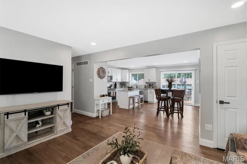 Hardwood-style flooring throughout, recessed lighting, and a kitchen featuring white cabinetry, a central island, and a sliding glass door — 7 Saint Mark Drive, St Peters, MO 63376