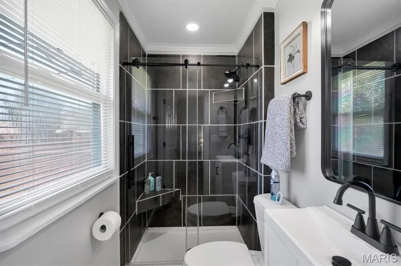 Tiled shower with glass enclosure, integrated shower bench, and matte black fixtures — 7 Saint Mark Drive, St Peters, MO 63376