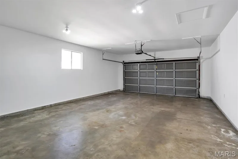 Spacious garage with a sectional overhead door, automatic opener, and concrete flooring — 7 Saint Mark Drive, St Peters, MO 63376