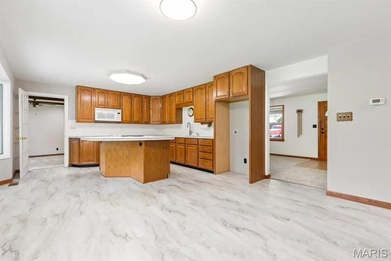 Kitchen features a center island and lots of wood cabinetry with under cabinet lighting plus new luxury vinyl tile — 14 Connie Drive, St Charles, MO 63301