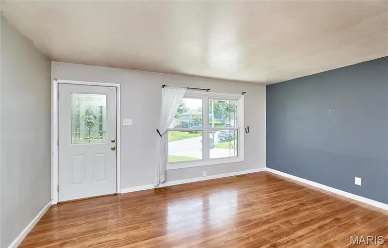 Wood-finish flooring, accent wall, and a window with white trim — 318 Capri Drive, O'Fallon, MO 63366