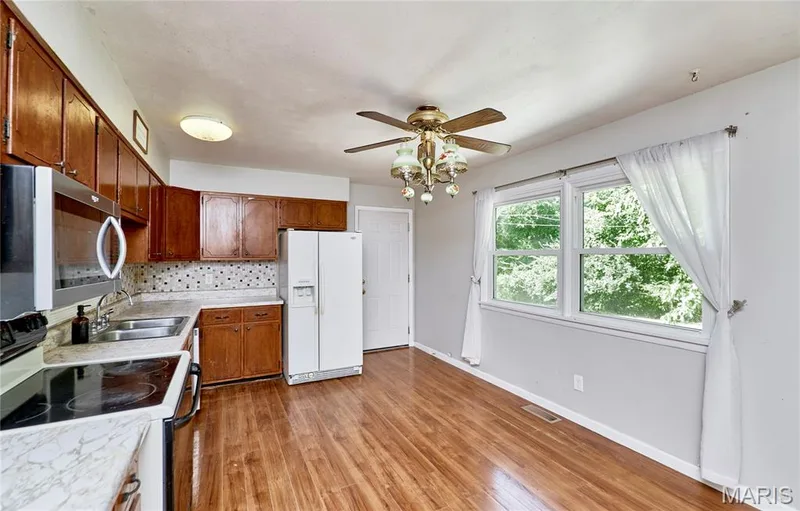 Wood-finish flooring, white appliances, built-in cabinetry, dual-basin sink, and a decorative ceiling fan — 318 Capri Drive, O'Fallon, MO 63366
