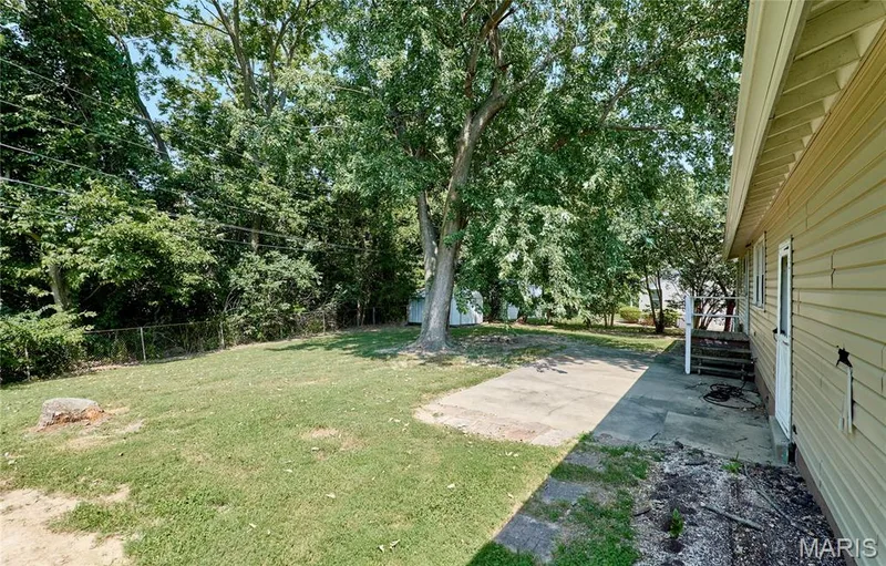 Expansive lawn with mature trees and a concrete patio — 318 Capri Drive, O'Fallon, MO 63366