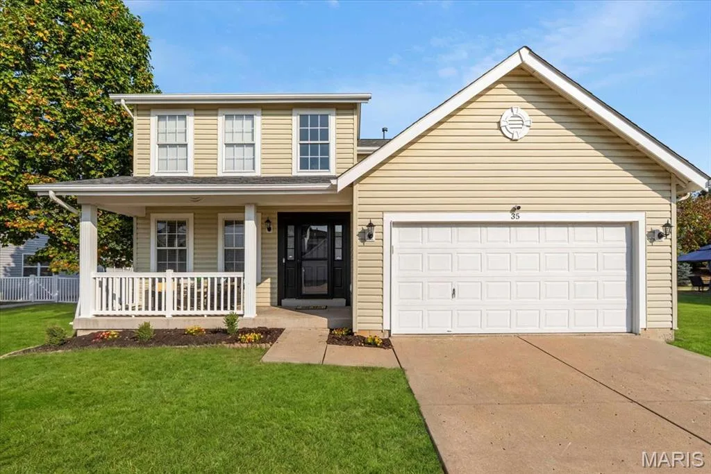 Two-story residence featuring a covered front porch, white railing, and a two-car garage — 35 Snowmass Court, O'Fallon, MO 63368