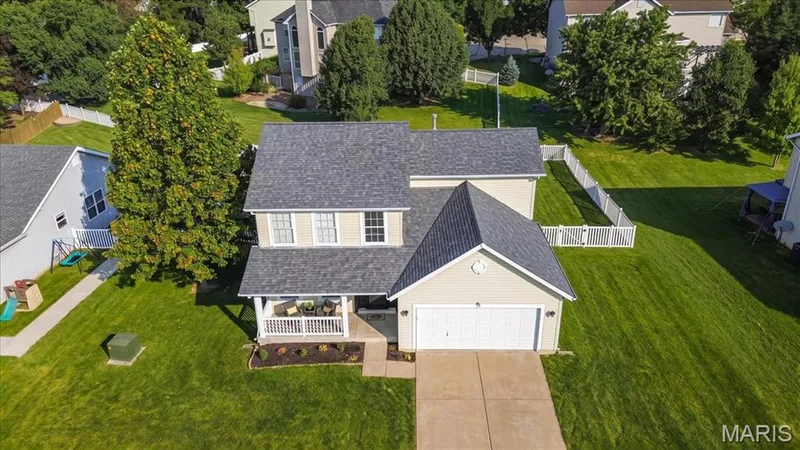Two-story exterior with a covered front porch, attached garage, concrete driveway, and a fenced backyard — 35 Snowmass Court, O'Fallon, MO 63368