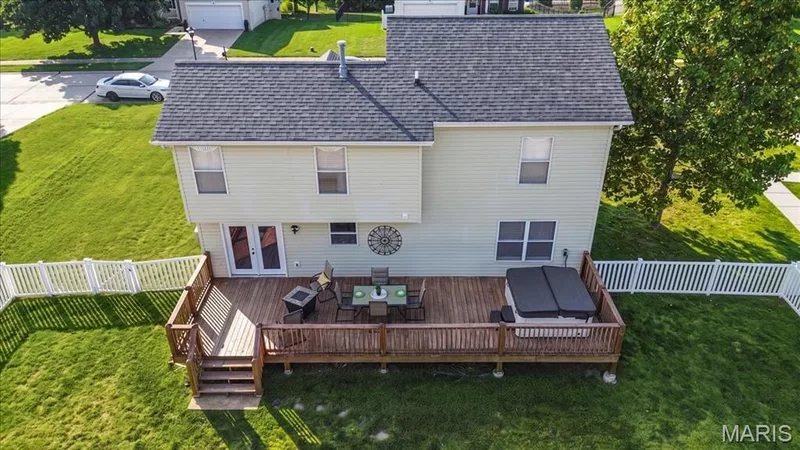 Expansive wood-finish deck with integrated steps, white picket fencing, and a spa — 35 Snowmass Court, O'Fallon, MO 63368
