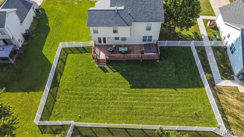 Expansive backyard with professionally manicured lawn, white vinyl fencing, and mature landscaping — 35 Snowmass Court, O'Fallon, MO 63368