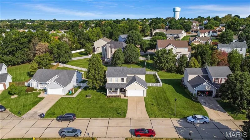Suburban setting featuring multiple residential properties with pitched roofs, front-facing garages, and paved driveways — 35 Snowmass Court, O'Fallon, MO 63368