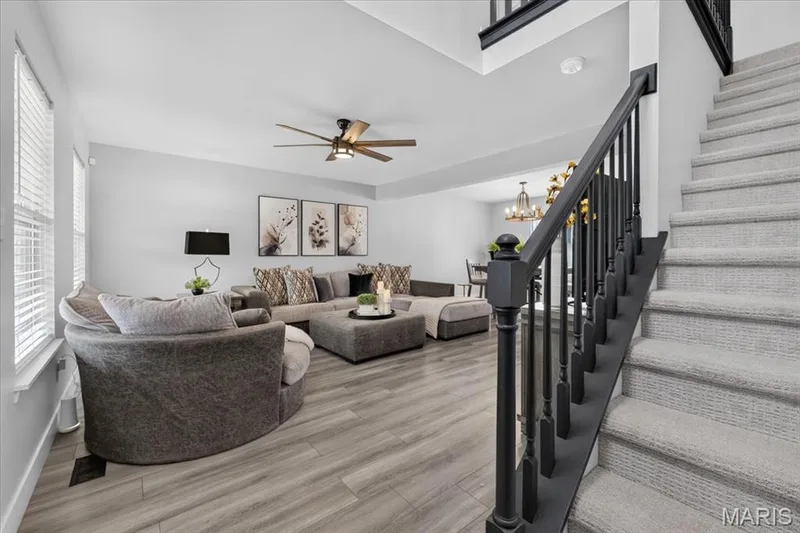 Spacious living area featuring wood-finish flooring, a ceiling fan, and multiple windows — 35 Snowmass Court, O'Fallon, MO 63368