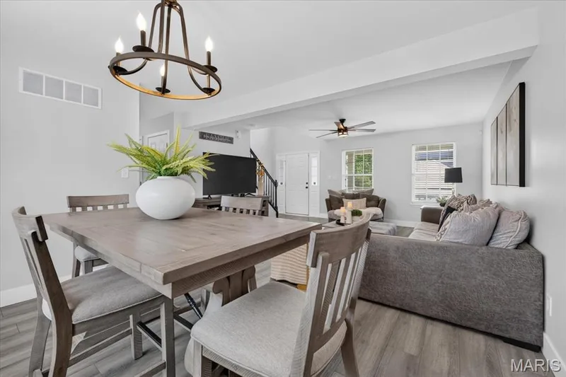 Open-concept living space with wood-finish flooring, a contemporary chandelier, and recessed lighting — 35 Snowmass Court, O'Fallon, MO 63368