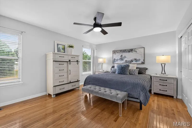Hardwood flooring, light gray wall finishes, multiple windows, and a ceiling fan with integrated lighting — 35 Snowmass Court, O'Fallon, MO 63368