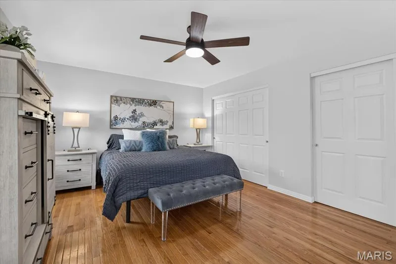 Hardwood flooring, ceiling fan with integrated lighting, two sets of white bi-fold closet doors, and light-toned walls — 35 Snowmass Court, O'Fallon, MO 63368