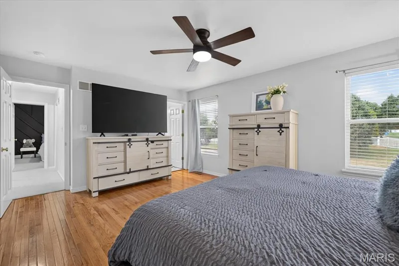 Hardwood flooring, ceiling fan with integrated lighting, two windows with blinds, and white trim throughout — 35 Snowmass Court, O'Fallon, MO 63368