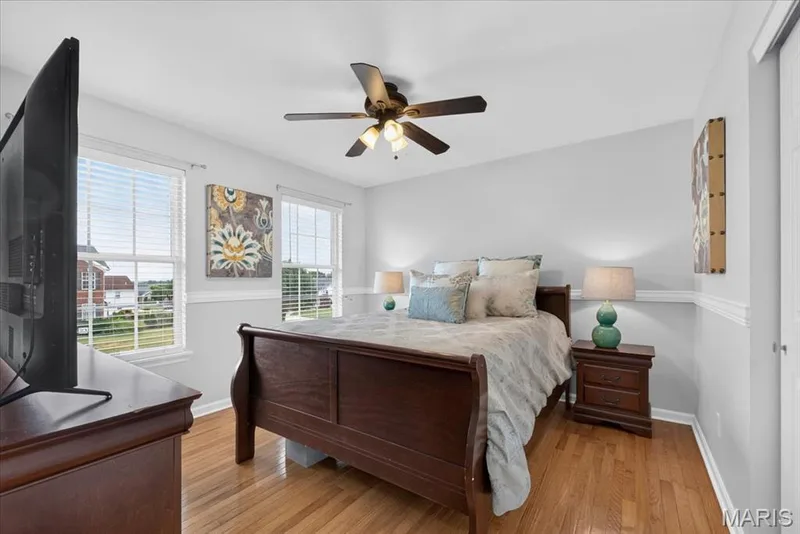 Hardwood flooring, two windows with blinds, ceiling fan with integrated lighting, two-tone wall treatment, and a built-in closet — 35 Snowmass Court, O'Fallon, MO 63368