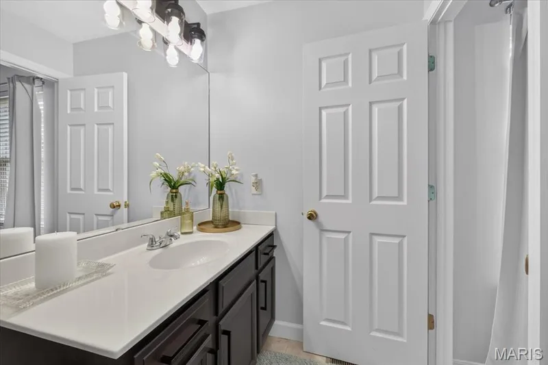 Vanity with a white countertop, undermount sink, and dark wood-finish cabinetry — 35 Snowmass Court, O'Fallon, MO 63368