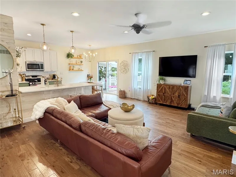 wood-finish flooring throughout, recessed ceiling lighting, ceiling fan, white upper cabinetry, and a kitchen island with white paneled base — 4024 Glengarry Drive, Wentzville, MO 63385