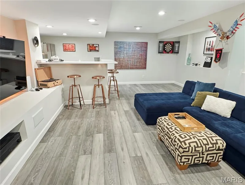 Recessed lighting illuminates the open-concept space, featuring LVP flooring, a built-in bar, and an integrated entertainment console — 4024 Glengarry Drive, Wentzville, MO 63385