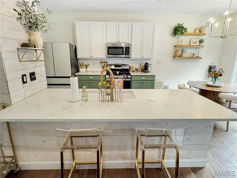 Kitchen featuring a large island with white stone countertop, white shaker cabinetry, stainless steel appliances, and a white backsplash — 4024 Glengarry Drive, Wentzville, MO 63385