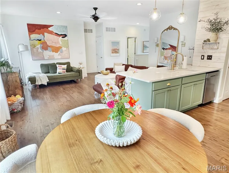 Wood-finish flooring throughout, kitchen island with light green cabinetry and white countertop, stainless steel dishwasher, and recessed lighting — 4024 Glengarry Drive, Wentzville, MO 63385