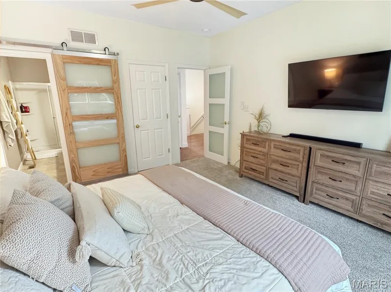 Vaulted ceiling with a ceiling fan, light-toned wall finishes, carpeted flooring, and a barn door with frosted glass panels — 4024 Glengarry Drive, Wentzville, MO 63385