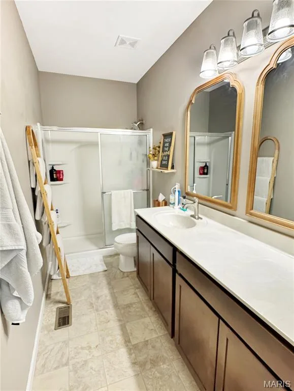 Dual basin vanity with an expansive countertop, wood-finish cabinetry, and framed mirrors — 4024 Glengarry Drive, Wentzville, MO 63385