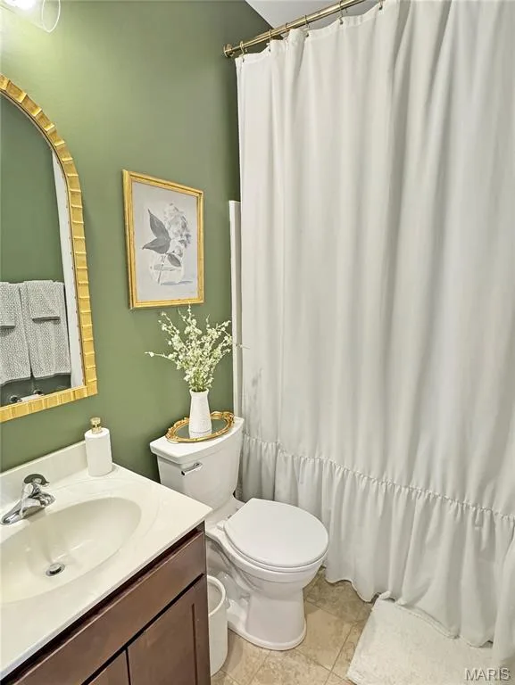 Vanity with an integrated sink and wood-finish cabinetry, a toilet, and a shower/tub combination with a shower curtain — 4024 Glengarry Drive, Wentzville, MO 63385