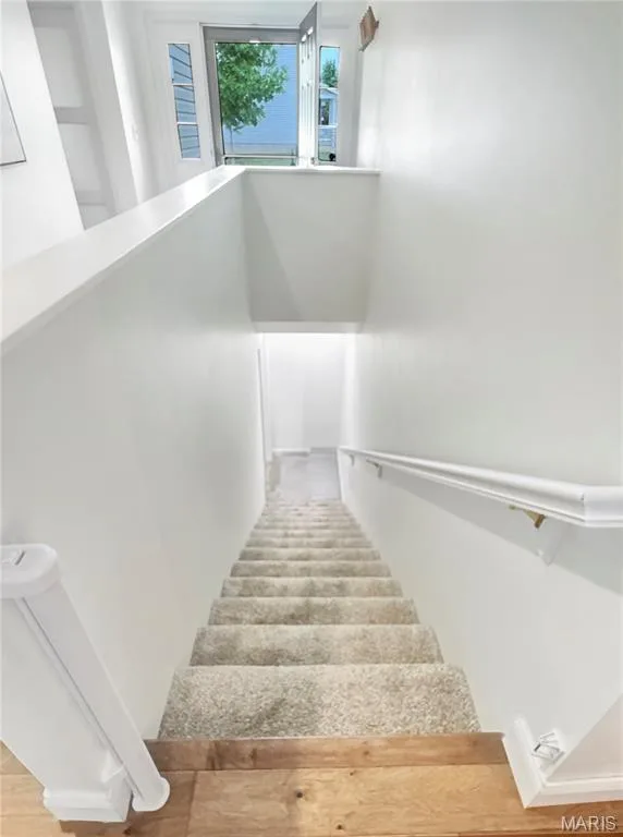 Staircase featuring light-toned carpeting and wood-finish flooring at the landing — 4024 Glengarry Drive, Wentzville, MO 63385