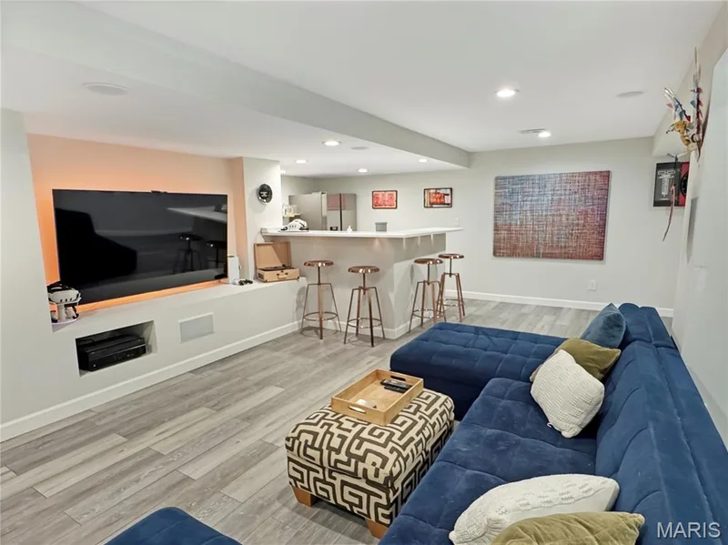 Recessed lighting, LVP flooring, built-in media console, integrated speakers, and a wet bar with seating — 4024 Glengarry Drive, Wentzville, MO 63385