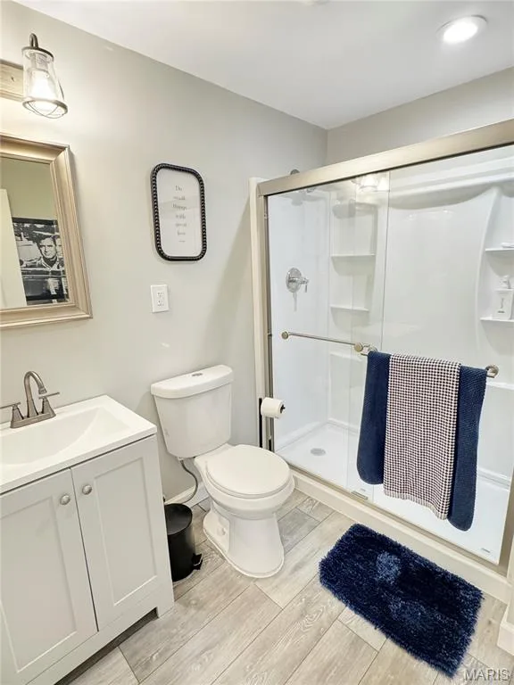 White vanity with a single basin sink, brushed nickel faucet, and wood-finish flooring — 4024 Glengarry Drive, Wentzville, MO 63385