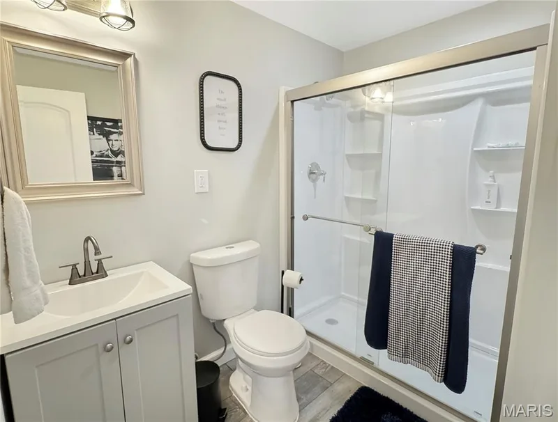 Modern vanity with an integrated sink and brushed nickel faucet, framed mirror, and a shower with sliding glass doors — 4024 Glengarry Drive, Wentzville, MO 63385