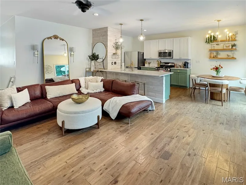 Open-concept living space featuring wood-finish flooring, a kitchen island with pendant lighting, and a dining area with a chandelier — 4024 Glengarry Drive, Wentzville, MO 63385