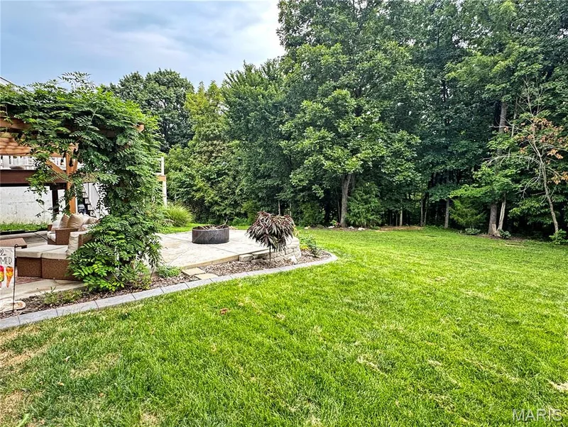 Expansive lawn area, concrete paver patio, wood pergola, built-in fire pit, and mature trees — 4024 Glengarry Drive, Wentzville, MO 63385