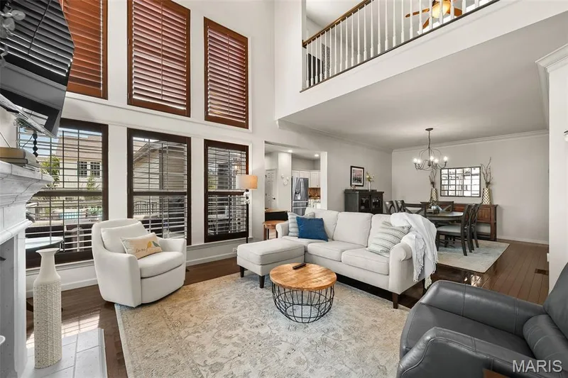 Two-story ceiling, wood-finish flooring, white fireplace surround, upper-level railing, and crown molding — 2700 Grover Crossing Drive, Wildwood, MO 63040