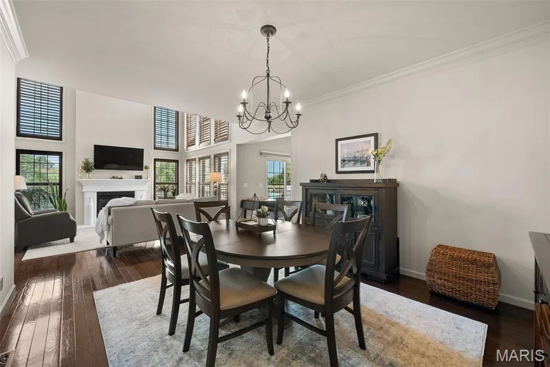 Hardwood flooring, crown molding, white fireplace with mantel, and high ceilings with multiple windows featuring plantation shutters — 2700 Grover Crossing Drive, Wildwood, MO 63040