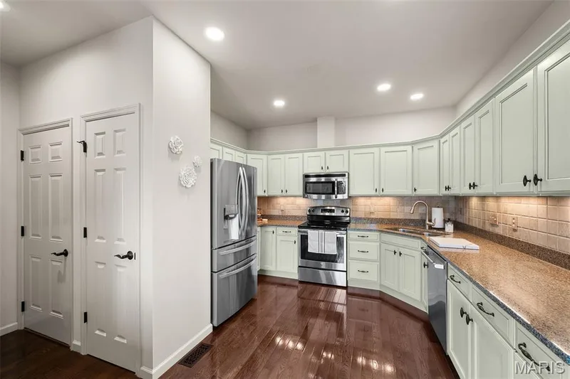 Kitchen featuring stainless steel appliances, light-toned cabinetry, natural stone countertops, and wood-finish flooring — 2700 Grover Crossing Drive, Wildwood, MO 63040