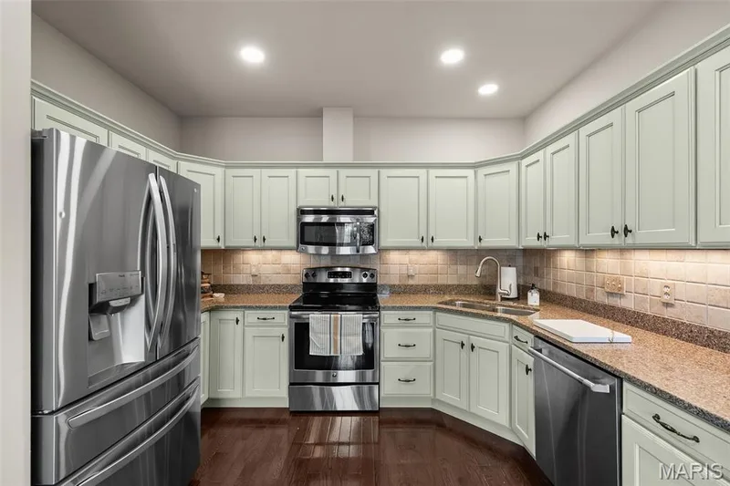 Kitchen featuring wood-finish flooring, light cabinetry with dark hardware, stainless steel appliances, and stone countertops — 2700 Grover Crossing Drive, Wildwood, MO 63040