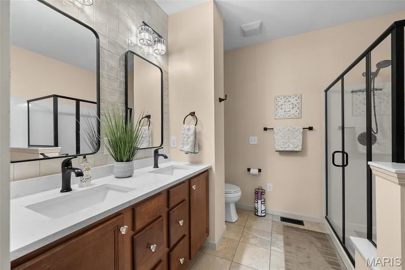Dual vanities with white countertops, black matte faucets, and rectangular mirrors — 2700 Grover Crossing Drive, Wildwood, MO 63040