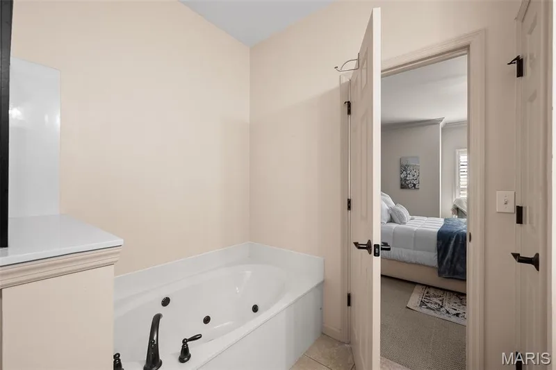 Soaking tub with dark-finish fixtures and light-toned tile flooring — 2700 Grover Crossing Drive, Wildwood, MO 63040