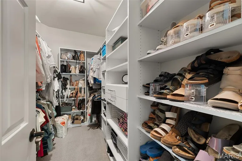 Walk-in closet featuring extensive built-in shelving, integrated drawers, and dedicated shoe storage — 2700 Grover Crossing Drive, Wildwood, MO 63040