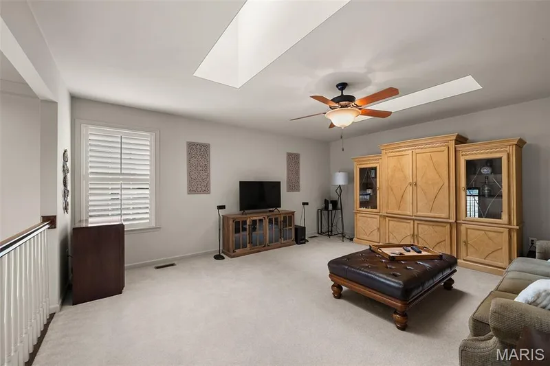 Bright interior with a skylight, ceiling fan, carpeted flooring, and white window shutters — 2700 Grover Crossing Drive, Wildwood, MO 63040