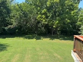 Expansive lawn area with mature trees and a wood-finish deck railing — 3641 Wind Chime Lane, St Charles, MO 63301