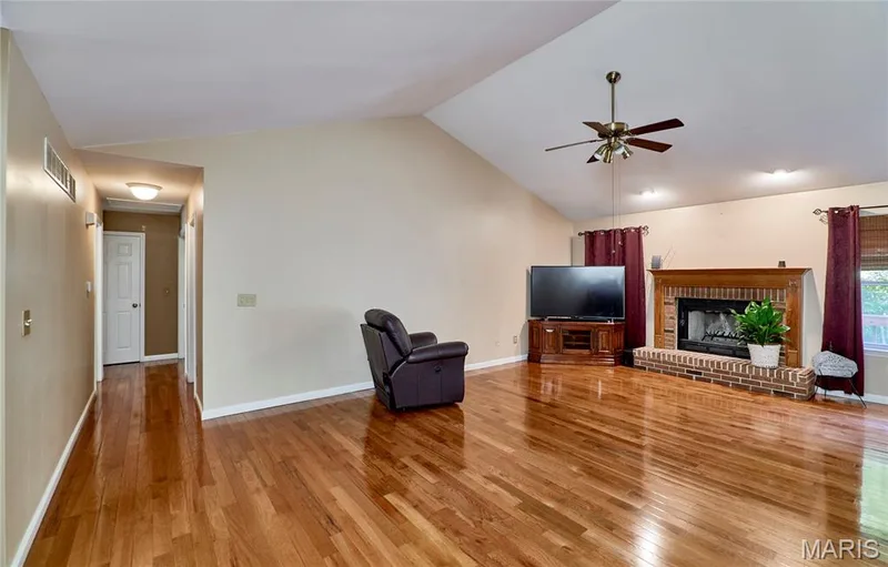 Vaulted ceiling with a ceiling fan, wood-finish flooring, brick-surround fireplace with wood mantel, and recessed lighting — 3641 Wind Chime Lane, St Charles, MO 63301