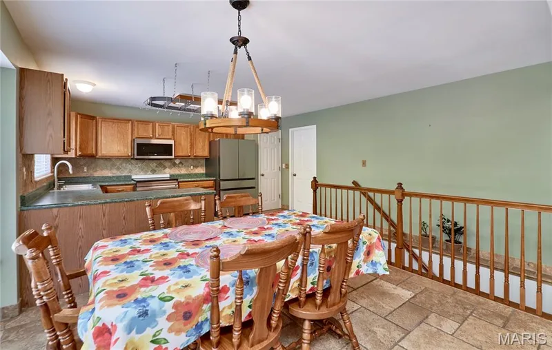 Kitchen and dining area featuring wood cabinetry, stainless steel appliances, and a tile backsplash — 3641 Wind Chime Lane, St Charles, MO 63301