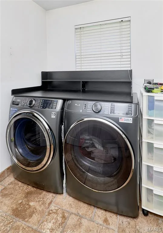 Modern laundry room featuring two large-capacity front-load washers and dryers with stainless steel finishes and digital control panels — 3641 Wind Chime Lane, St Charles, MO 63301