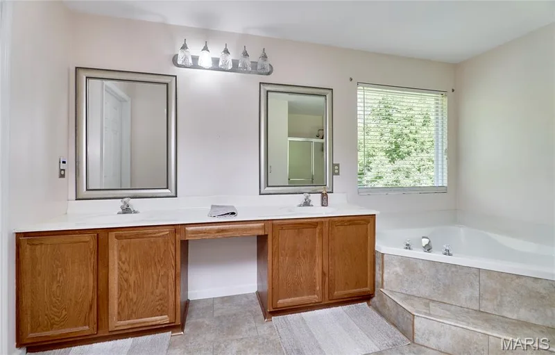 Dual vanity with wood-finish cabinetry and rectangular framed mirrors — 3641 Wind Chime Lane, St Charles, MO 63301